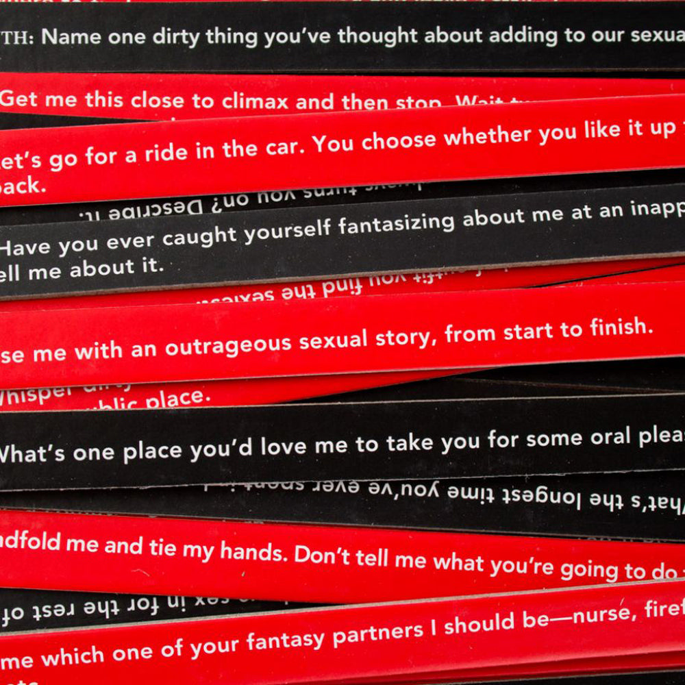 The image shows a collection of red and black sticks with written prompts for a party game called 'Sexy Truth or Dare'. 