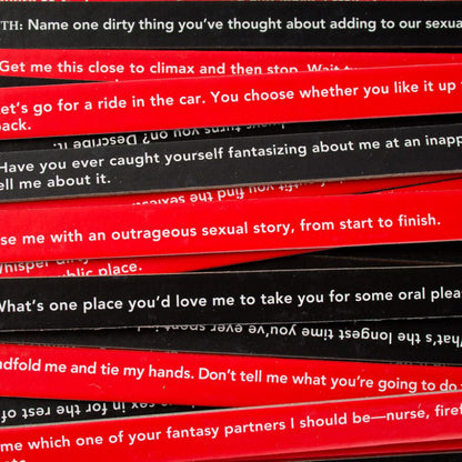 The image shows a collection of red and black sticks with written prompts for a party game called 'Sexy Truth or Dare'. 