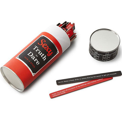 The image shows a collection of red and black sticks with written prompts for a party game called 'Sexy Truth or Dare'. These are contained in a cylindrical red container with a label that reads 'Sexy Truth or Dare'.