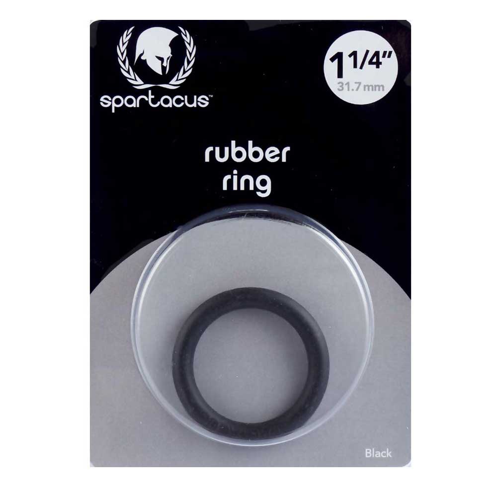 A black rubber cock ring by Spartacus, packaged in a clear plastic case with a black and white label. The ring is visible through the case, indicating a snug fit for controlling ejaculation and enhancing performance.