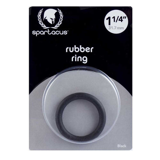 A black rubber cock ring by Spartacus, packaged in a clear plastic case with a black and white label. The ring is visible through the case, indicating a snug fit for controlling ejaculation and enhancing performance.
