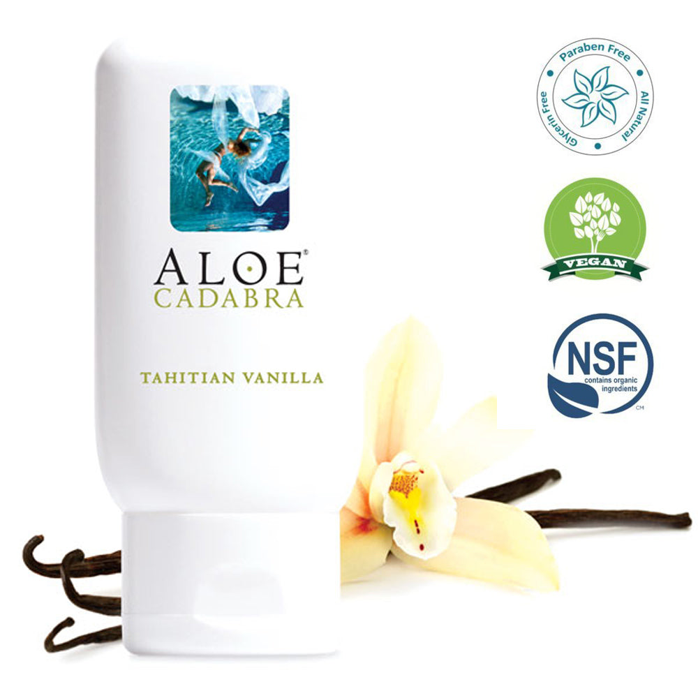 A bottle of Aloe Cadabra Tahitian Vanilla lubricant with a white and blue label, next to a vanilla flower. To the right are labels that describe that the product is free of glycerin and paraben, is vegan, and is made with organic ingredients.